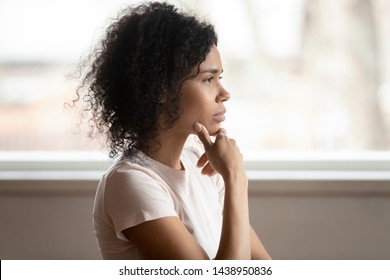Pensive Mixed Race 30s Woman Sitting At Home Touch Chin Lost On Deep Thoughts Thinking Makes Decision, Side View Face, Challenge, Problems Solution, Solving Issues, Consideration Or Brain Work Concept