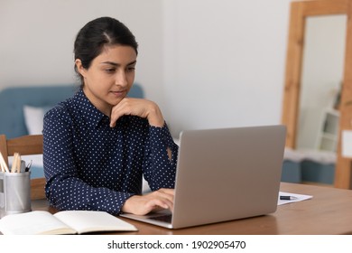 Pensive Mixed Race Female University Student On Distant Learning Sit By Laptop Think On Problem Solution Look For Answer Test Exam Questions. Focused Young Indian Woman Analyse Data On Computer Screen