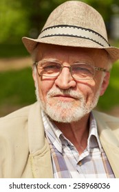 Pensive Old Man With Hat And Glasses Sitting In A Park In Fall