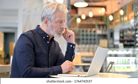 Pensive Old Man Using Laptop In Cafe