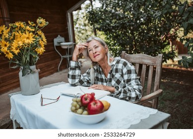 Pensive older women is sitting in the garden and writing in her diary. Female senior is keeping daily journal, writing down thoughts and feelings. - Powered by Shutterstock