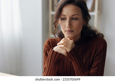 Pensive Pondering Unhappy Sad Curly Beautiful Woman Lost In Heavy Thoughts Looks Down Think About Difficult Life Decision Sitting At Home Office. People Problems Concept