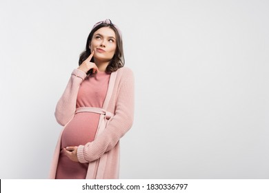 pensive pregnant woman in headband touching face and looking up isolated on white
