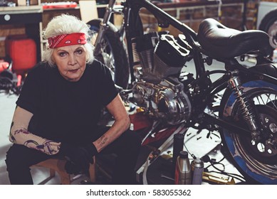 Pensive retiree sitting next to motorcycle - Powered by Shutterstock