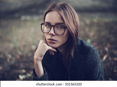 Pensive sad beautiful young woman in stylish sunglasses closeup on a city street