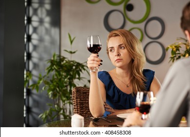 Pensive sad woman with glass of wine looking at window during th date - Powered by Shutterstock