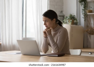 Pensive satisfied freelance employee woman working in home kitchen, sitting at laptop on table, thinking over online project future vision, planning task, job success, career achieve - Shutterstock ID 2161634987
