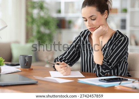 Pensive self employed trying to write a letter working at home