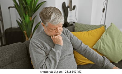 Pensive senior man with gray hair sitting pensively in a modern living room. - Powered by Shutterstock