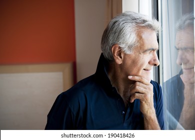 Pensive Senior Man Looking Outside The Window