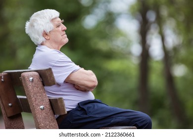 Pensive senior man sitting on bench in summer park - Powered by Shutterstock