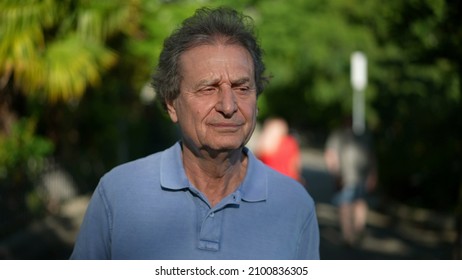 Pensive Senior Man Walking Outside In City Green Nature Path