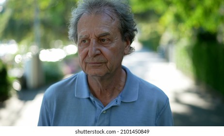 Pensive Senior Man Walking Outside In City Green Nature Path