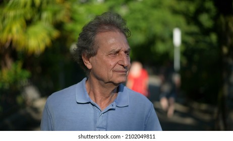 Pensive Senior Man Walking Outside In City Green Nature Path