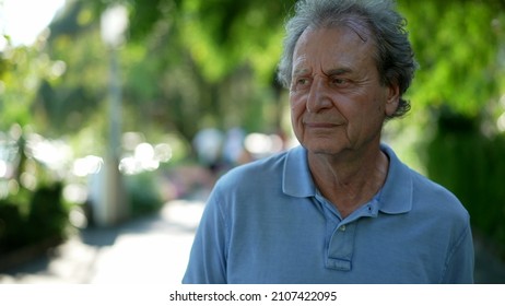 Pensive Senior Man Walking Outside In City Green Nature Path