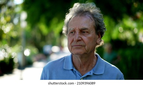 Pensive Senior Man Walking Outside In City Green Nature Path