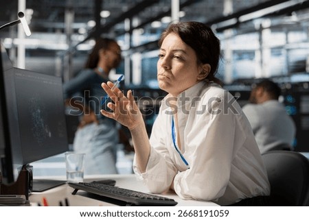 Pensive server hub engineer looking at data visualization on PC, thinking how to fix performance issues. Data center worker looks at analysis graph, brainstorming how to repair hardware failures