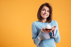 Pensive Smiling Young Woman Holding Cupcake And Thinnking