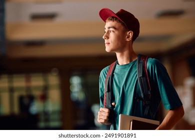 Pensive teenage boy in high school hallway looking away. Copy space.