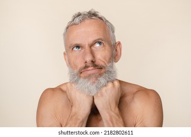 Pensive Thoughtful Caucasian Mature Middle-aged Man With Bare Shoulders Naked Shirtless Looking Upwards Thinking About Male Body Skin Care Beauty Isolated In Beige Background