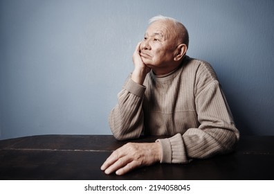 Pensive and thoughtful senior man sitting at the table - Powered by Shutterstock