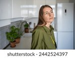 Pensive thoughtful woman with distressed mood stands in kitchen of home. Anxiety fear. Tired frustrated blonde woman feel bad, looking sadly away. Mid-life crisis, despair, sadness, negative emotions.