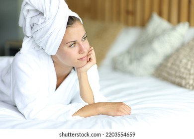 Pensive woman after showering contemplating lying on the bed at home - Powered by Shutterstock