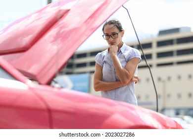 Pensive woman looks at car engine closeup - Powered by Shutterstock