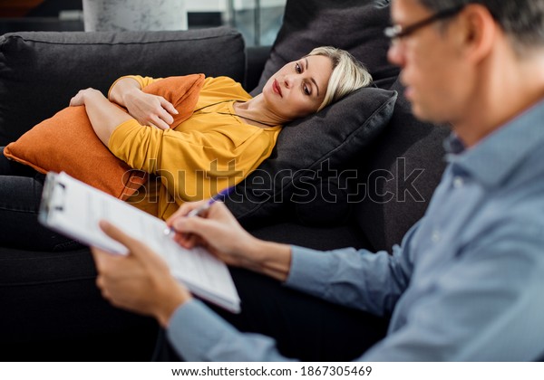 Pensive woman lying down on psychiatrist\'s couch during\
a therapy session. 