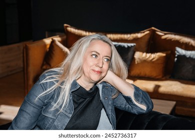 Pensive Woman with Platinum Blonde Hair Relaxing in a Denim Jacket Indoors - Powered by Shutterstock