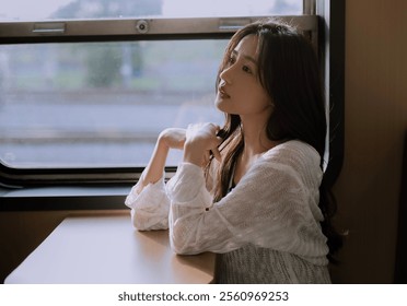 Pensive Woman Sitting by a Train Window in Soft Natural Light, Radiating Serenity and Thoughtfulness – Perfect for Travel or Lifestyle Themes. - Powered by Shutterstock