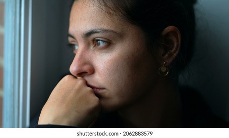 Pensive woman sitting by window looking outside. Close-up thoughtful person - Powered by Shutterstock