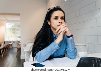 pensive woman sitting in office at table