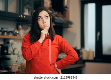 
Pensive Woman Standing In The Kitchen Thinking About Food. Young Person In Doubt Making A Mental Meal Plan Menu
