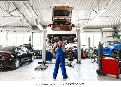 Pensive young African mechanic in car service looking at car thinking of how to repair it - Powered by Shutterstock