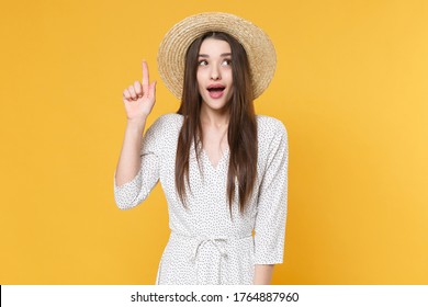 Pensive Young Brunette Woman Girl In White Dress Hat Posing Isolated On Yellow Background Studio Portrait. People Lifestyle Concept. Mock Up Copy Space. Holding Index Finger Up With Great New Idea