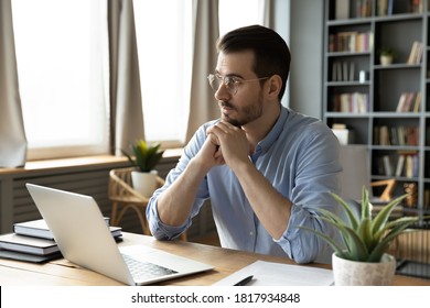 Pensive Young Caucasian Male Worker In Glasses Distracted Form Laptop Work Look In Window Distance Thinking Pondering. Thoughtful Man Busy At Computer Make Decision Plan At Home Office Workplace.