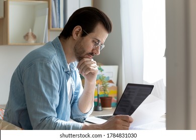 Pensive Young Caucasian Man In Glasses Work On Laptop Read Analyze Postal Paperwork At Home Workplace, Thoughtful Millennial Male Consider Post Paper Correspondence Or Letter News Document