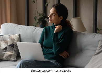 Pensive Young Caucasian Woman Sit On Couch At Home Work Online On Laptop Look In Distance Thinking Pondering. Thoughtful Millennial Female Distracted From Computer Planning Or Deciding.