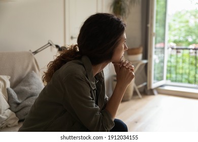 Pensive young Caucasian woman sit on sofa at home look in distance think ponder of family problem solution. Unhappy thoughtful millennial female troubled lost in thoughts, consider breakup or divorce. - Shutterstock ID 1912034155