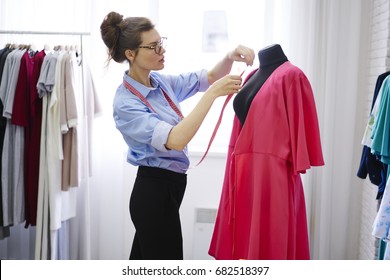 Pensive young designer using tape for measuring mannequin creating pret-a-porter collection in showroom, concentrated owner of fashion industry business working in atelier on tailoring samples - Shutterstock ID 682518397