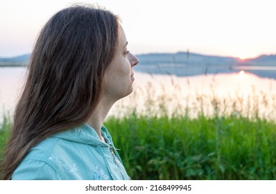 Pensive Young Girl Looking At Sunset On River On Summer Evening. Alone With Nature. Relaxation Or Vacations In Nature. Mental Health. Staycation Or Unplugged Concept. Close Up. Selective Focus.