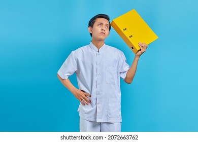 Pensive Young Male Nurse Holding Folder And Looking Aside On Blue Background