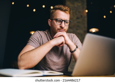 Pensive young man attentively watching webinar on laptop computer while studying. Redhead male freelancer thoughtfully work on project solution on netbook. Caucasian student training online - Powered by Shutterstock