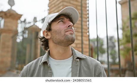 Pensive young man with beard in casual clothes looking up in a sunny urban street setting - Powered by Shutterstock