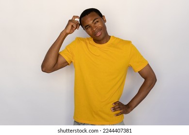 Pensive young man scratching his head thinking. Male African American model with brown eyes and short black haircut in yellow T-shirt looking away making decision. Thought, advertisement concept - Shutterstock ID 2244407381