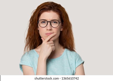 Pensive young red-haired young woman isolated on grey background look at camera thinking, thoughtful redhead girl in glasses pondering planning problem solution, lost in thoughts consider idea - Shutterstock ID 1365610742