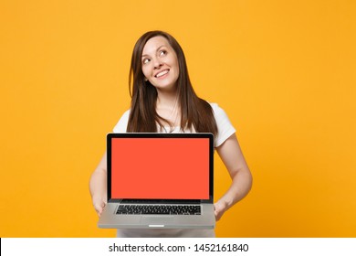 Pensive Young Woman In White Casual Clothes Holding Laptop Pc Computer With Blank Empty Screen Isolated On Bright Yellow Orange Wall Background In Studio. People Lifestyle Concept. Mock Up Copy Space