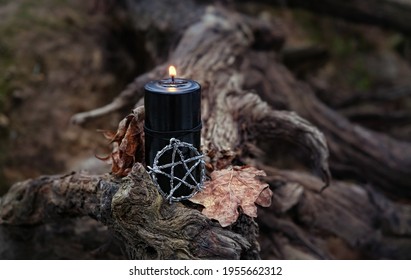 Pentagram Amulet And Black Candle In Autumn Forest, Natural Background. Magic Esoteric Witches Ritual. Mysticism, Divination, Wicca, Occultism, Witchcraft Concept. Samhain Sabbat, Halloween Holiday