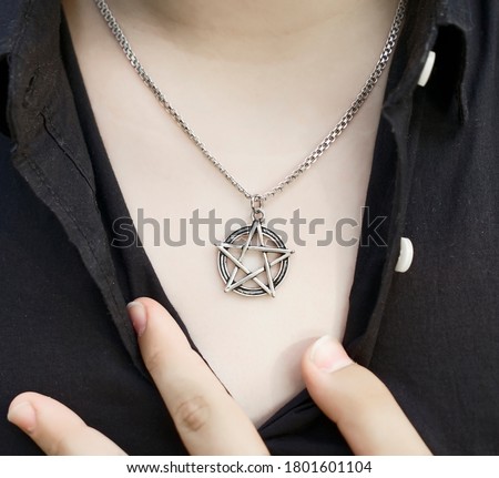 pentagram pendant on the chest of a woman. ring on male finger. close up image. In Freemasonry, the five-pointed star symbolizes light, knowledge and perfection. 